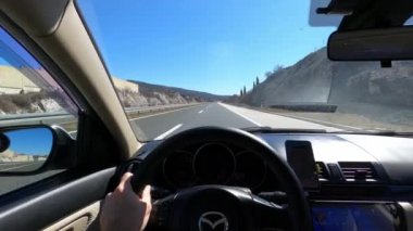 Adam bir dağ yolunda mavi bir ufka doğru araba sürüyor. Yüksek kalite 4k görüntü