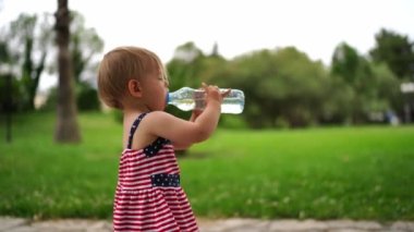 Parkta duran bir şişeden su içen küçük kız. Yüksek kalite 4k görüntü