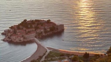 Kotor Körfezi 'ndeki Sveti Stefan adası batan güneşin yansımalarında. Yüksek kalite 4k görüntü