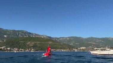 Kırmızı motorlu tekne dağlık bir sahile doğru deniz boyunca yüzer. Arkadan bak. Yüksek kalite 4k görüntü