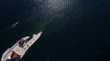 Tekne, Kotor Körfezi 'ndeki Kayalıklardaki Meryem Kilisesi' nin yanından geçiyor. Drone. Yüksek kalite 4k görüntü