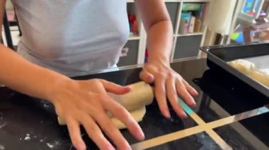 Baker ekmeğin hamurunu masanın üzerinde merdaneyle yuvarlıyor. Yüksek kalite 4k görüntü