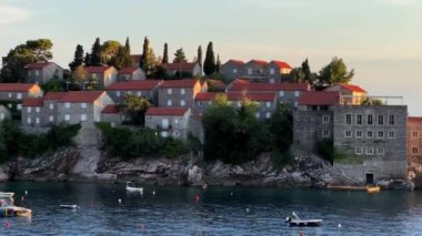 Sveti Stefan adasının açıklarındaki dalgalarda küçük tekneler sallanıyor. Karadağ. Yüksek kalite 4k görüntü