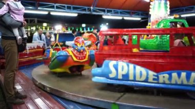 Çocuklu ebeveynler lunaparkta renkli bir atlıkarıncaya biniyorlar. Yüksek kalite 4k görüntü