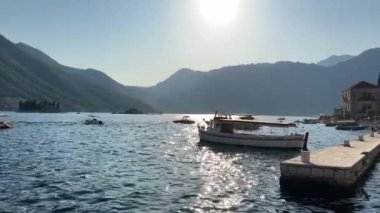 Perast kıyısında, rıhtımda demirli teknelerle dağların arka planına karşı. Karadağ. Yüksek kalite 4k görüntü