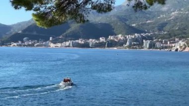 Motorlu tekne tatil köyünün dağ kıyısına doğru yelken açar. Yüksek kalite 4k görüntü