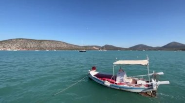 Balıkçı teknesi dalgalar üzerinde sallanıyor. Rıhtımda, dağların arka planında. Yüksek kalite 4k görüntü