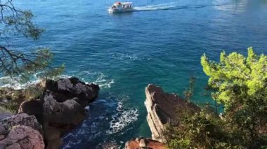 Bir uçurumdan, dağların arka planına karşı denizde seyreden gezici bir tekneye bakmak. Yüksek kalite 4k görüntü