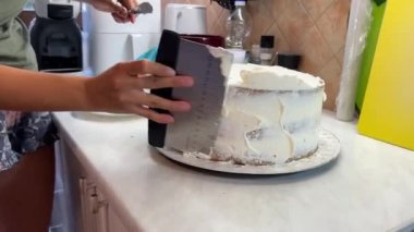 Baker pastanın kenarlarına spatula ve bıçakla krem sürüyor. Yüksek kalite 4k görüntü