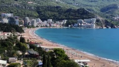 Kumsalda kumsalda, yeşil dağların eteklerindeki deniz kıyısında güneşlenirler. Yüksek kalite 4k görüntü