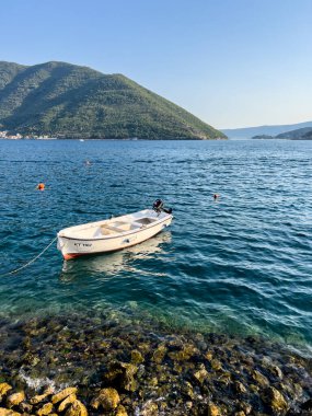 Beyaz balıkçı teknesi, dağların arka planına karşı sığ sularda demirlemiş. Yüksek kalite fotoğraf