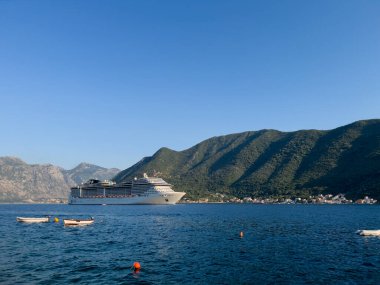 Büyük yolcu gemisi Kotor Körfezi boyunca yeşil dağların arka planına doğru yelken açıyor. Karadağ. Yüksek kalite fotoğraf