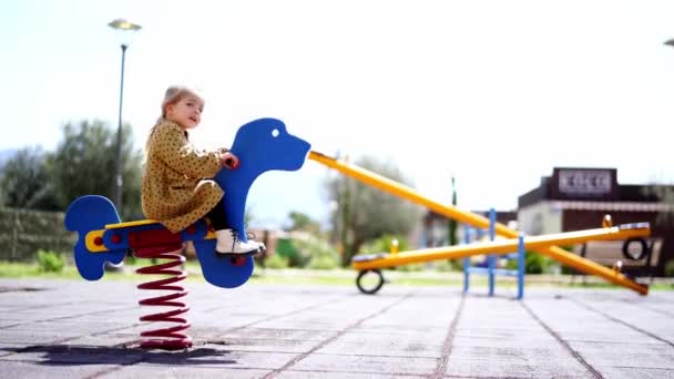 Little Girl Swings Swing Spring Playground Holding Handles Side View — Stock Video