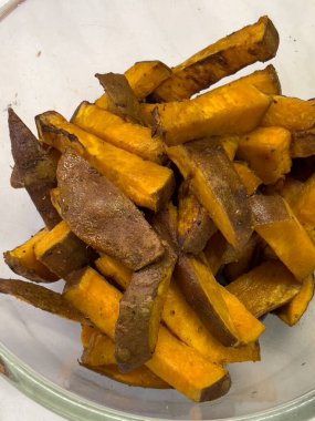 Fırında pişmiş tatlı patates parçaları derin bir cam kasede yatıyor. Yüksek kalite fotoğraf