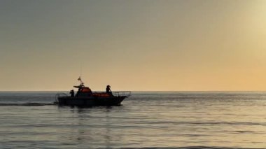Sürat teknesi ufuktaki güneşin yansımalarıyla denizde yüzer. Yüksek kalite 4k görüntü