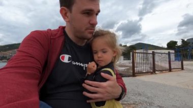 Babam iskelede oturuyor ve küçük bir kıza sarılıyor. Yüksek kalite 4k görüntü