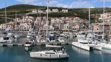Küçük yat Lustica Körfezi boyunca yelken açıyor. Marinayı geçiyor. Yüksek kalite 4k görüntü