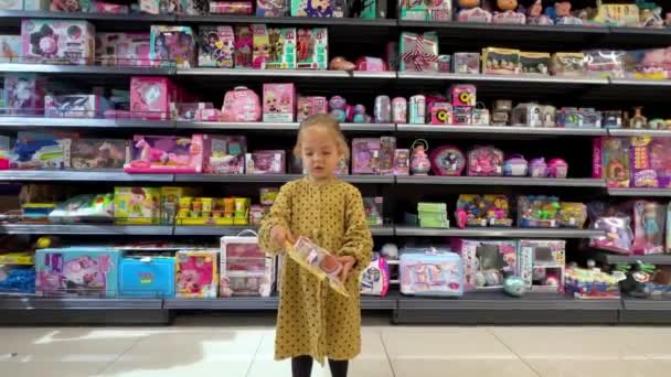 Klein Meisje Kiest Een Kleurrijk Speelgoedsetje Een Supermarkt Hoge Kwaliteit — Stockvideo