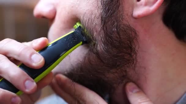 Seorang Pria Mencukur Pipinya Dengan Pisau Cukur Listrik Sambil Memegang — Stok Video