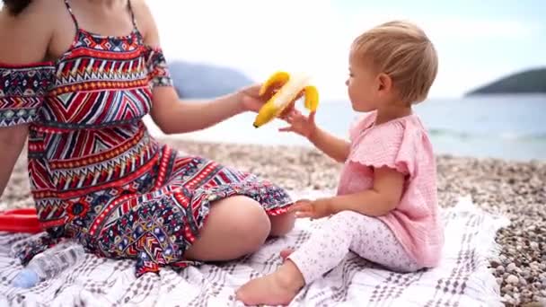 Μαμά Δίνει Ένα Κοριτσάκι Μια Ξεφλουδισμένη Μπανάνα Ενώ Κάθεται Μια — Αρχείο Βίντεο