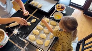 Annem küçük kızının tepsideki çöreklere susam serpmesine yardım ediyor. Yüksek kalite 4k görüntü