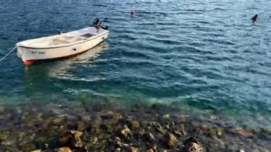 Balıkçı teknesi dalgalar üzerinde dalgalanan kayalık bir kıyıya demirledi. Yüksek kalite 4k görüntü