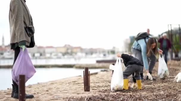 Små Flickor Med Sina Mödrar Samlar Skräp Stranden Påsar Högkvalitativ — Stockvideo