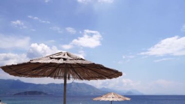 Saman güneş şemsiyeleri deniz kenarında rüzgarda sallanıyor. Yüksek kalite 4k görüntü