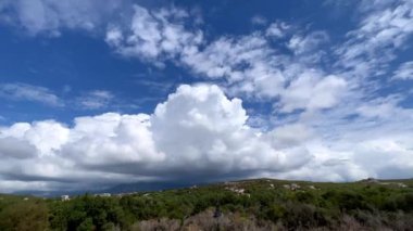 Mavi gökyüzünde yeşil dağların üzerinde beyaz kümülüs bulutları. Panorama. Yüksek kalite 4k görüntü