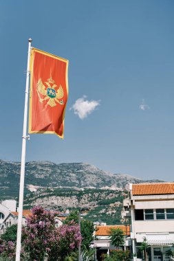 Karadağ bayrağı, dağların eteğindeki evlerin arka planında bir bayrak direğinde dalgalanıyor. Yüksek kalite fotoğraf