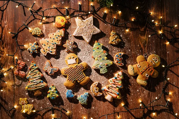 Colorful glazed cookies on a floured table among glowing garlands. Top view. High quality photo