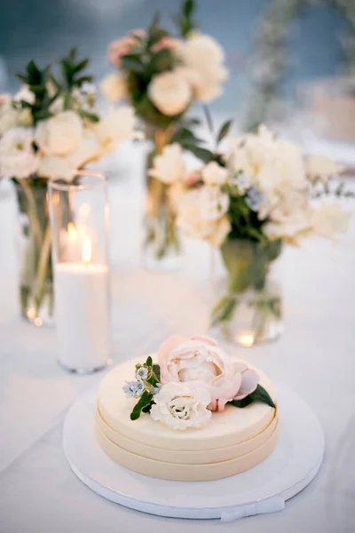 Wedding cake with floral decoration stands on a stand on the table. High quality photo