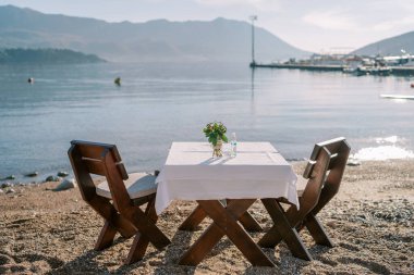Deniz kenarındaki kumlu bir plajda iki kişilik sandalyeli bir masa hazırladım. Yüksek kalite fotoğraf