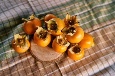 Olgun hurma yığını kareli bir masa örtüsü ve masanın üzerindeki ahşap yuvarlak bir tahtada yatıyor. Üst Manzara. Yüksek kalite fotoğraf