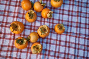 Olgun hurmalar masanın üzerindeki kareli peçetenin üzerinde yatar. Yüksek kalite fotoğraf