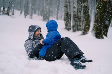 Gülen anne, karın altında karnında küçük bir çocukla karda yatıyor. Yüksek kalite fotoğraf