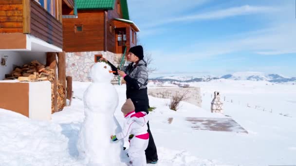 Mama Mit Einem Kleinen Mädchen Passt Eine Schneemannnase Karotte Und — Stockvideo