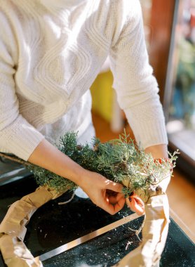 Sanatçı masanın üzerindeki Noel çelengine kozalaklı dallar takıyor. Yüksek kalite fotoğraf
