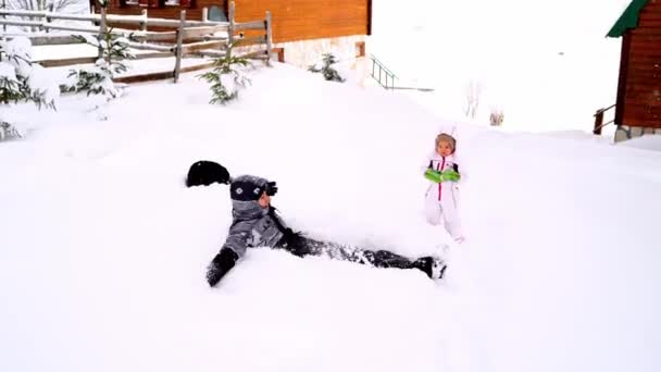 Mam Valt Sneeuw Bij Een Klein Meisje Maakt Een Sneeuwengel — Stockvideo