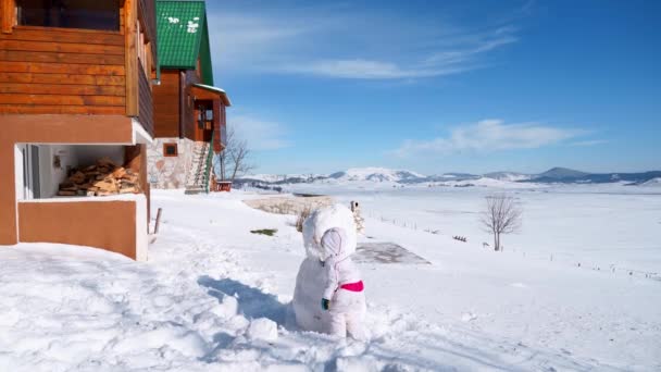 Klein Meisje Beeldhouwt Een Grote Sneeuwpop Buurt Van Het Huis — Stockvideo
