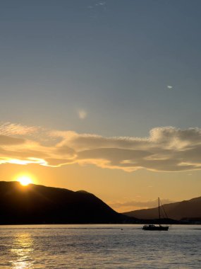 Yelkenli yat, gün batımının arka planına karşı, dağların üzerinde yüzüyor. Yüksek kalite fotoğraf