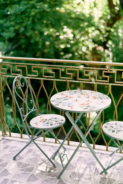 Small round table with chairs with backs stands on the balcony of the house. High quality photo