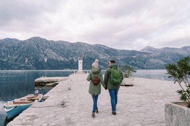 Çift deniz fenerine doğru el ele tutuşarak yürüyor. Arkadan bak. Yüksek kalite fotoğraf