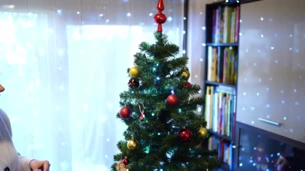 Κορίτσι Κρεμάει Παιχνίδια Στο Χριστουγεννιάτικο Δέντρο Δίπλα Στην Κορυφή Υψηλής — Αρχείο Βίντεο