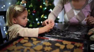 Annem küçük bir kızın hamura kurabiye bıçağı koymasına yardım ediyor. Yüksek kalite 4k görüntü