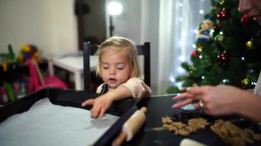 Küçük bir kızı olan bir anne masaya kıvırcık zencefilli kurabiyeler serer. Yüksek kalite 4k görüntü