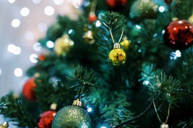 Altın, kırmızı ve yeşil toplar çelenklerin ışığında bir Noel ağacının dallarında asılı. Yüksek kalite fotoğraf