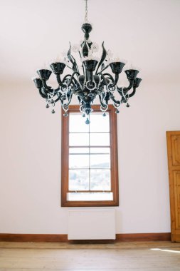 Pencerenin karşısındaki holün tavanında büyük siyah avize asılı. Yüksek kalite fotoğraf