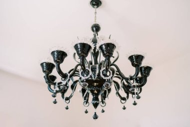 Açılış dekorlu ve kolyeli siyah avize villanın beyaz tavanında asılı duruyor. Yüksek kalite fotoğraf