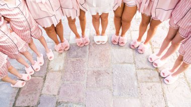 Bride and bridesmaids stand in pajamas and slippers on the tiles in a semicircle. Cropped. Faceless. High quality photo clipart